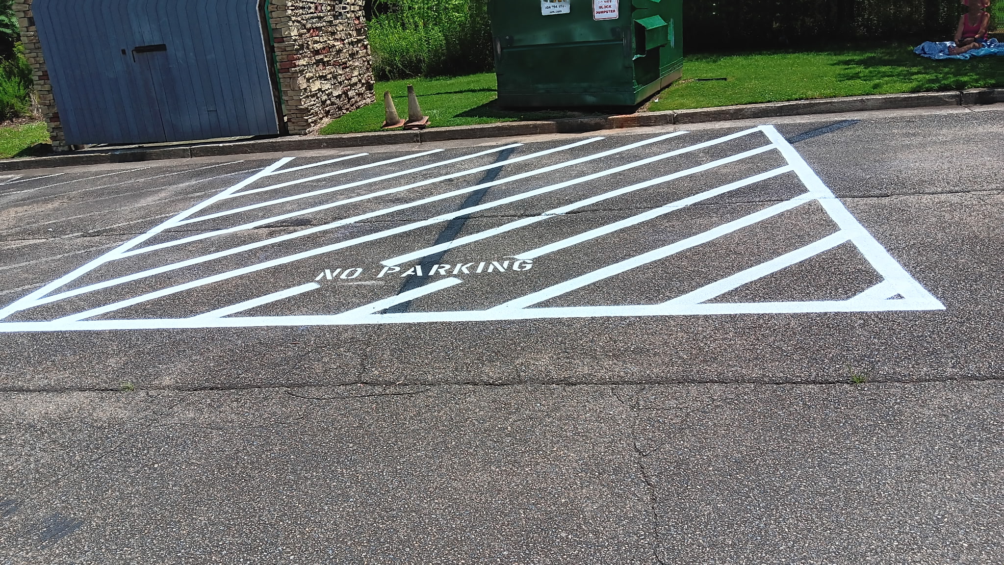 Fresh white no parking zone and diagonal pavement markings at a commercial property.