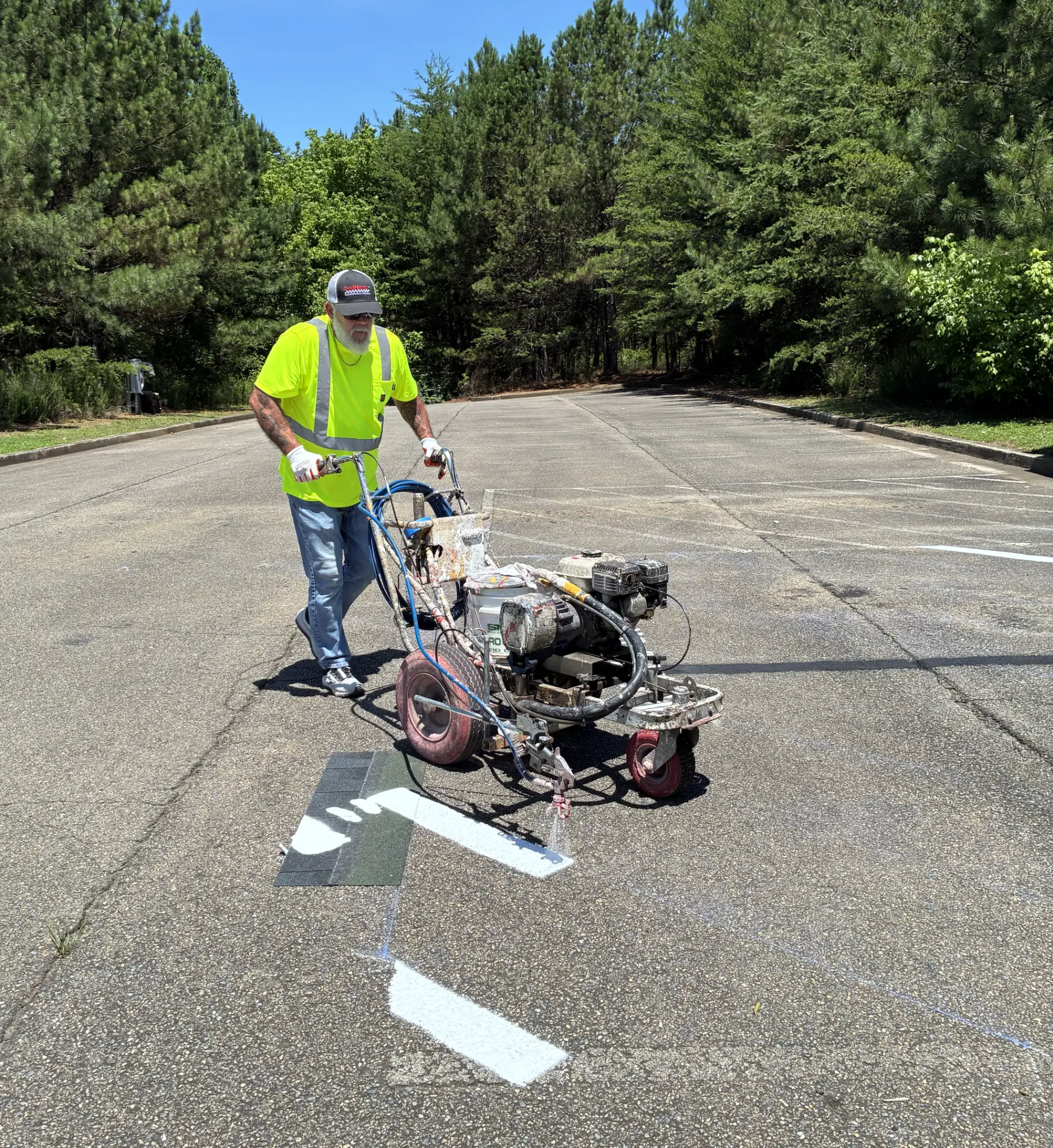 RoseCreek Striping technician applying fresh white traffic paint to a North & Middle Georgia commercial parking lot.
