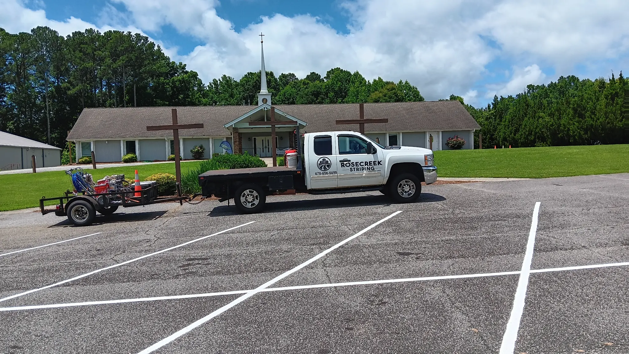 RoseCreek Striping truck and equipment trailer beside freshly striped commercial parking spaces in North & Middle Georgia.